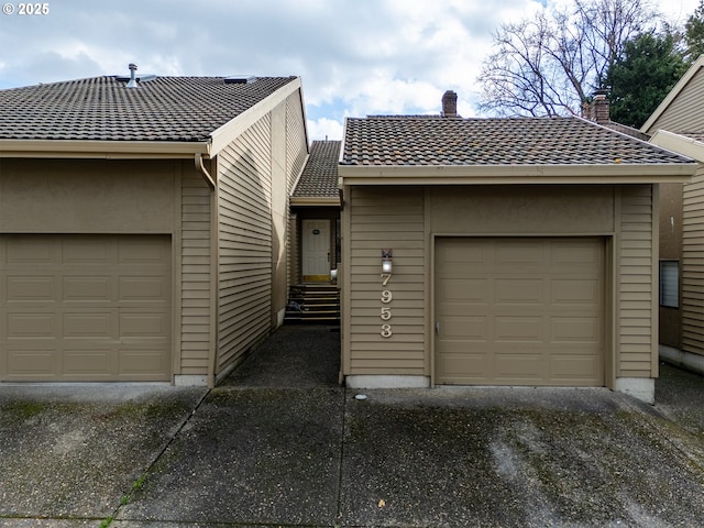 view of front of property with a garage, a tile roof, and a chimney