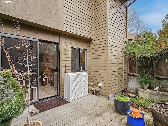 view of exterior entry with fence and a wooden deck