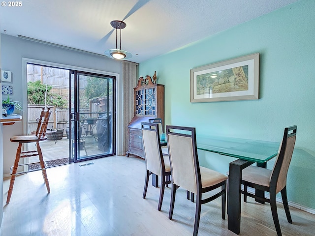 dining space featuring visible vents, baseboards, and wood finished floors