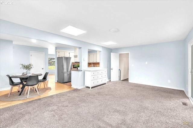 513 SE 103rd Ave, Vancouver, WA 98664 - kitchen with freestanding refrigerator, light colored carpet, white cabinets, a skylight, and baseboards