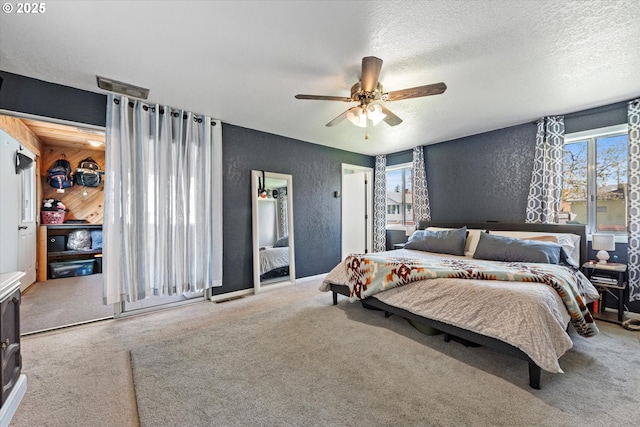 bedroom with carpet flooring, a ceiling fan, a textured ceiling, and a textured wall