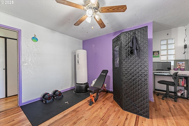 exercise room featuring wood finished floors, ceiling fan, and a textured ceiling