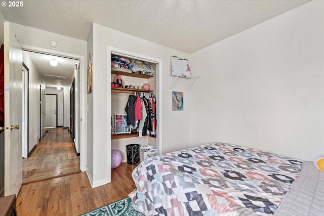 bedroom featuring wood finished floors, a textured ceiling, and a closet