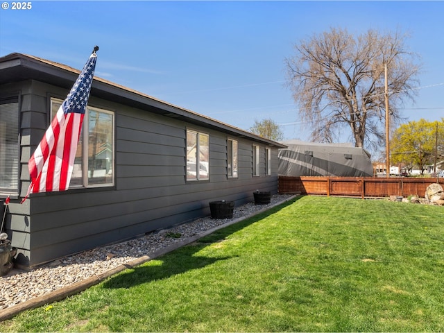 view of side of property with a lawn and fence
