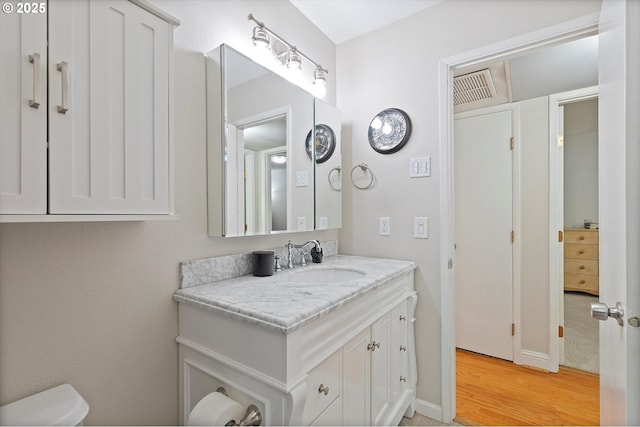 bathroom with wood finished floors, toilet, vanity, and baseboards