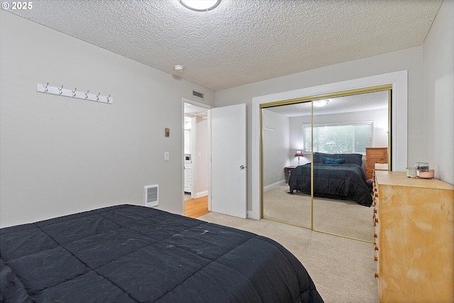 bedroom with light carpet, a textured ceiling, a closet, and baseboards