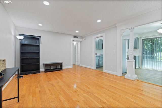 unfurnished living room with decorative columns, recessed lighting, light wood-style flooring, and a textured ceiling