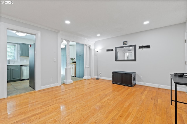 unfurnished living room with a sink, recessed lighting, light wood-style flooring, baseboards, and ornamental molding
