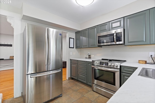 kitchen with appliances with stainless steel finishes, light countertops, and gray cabinets