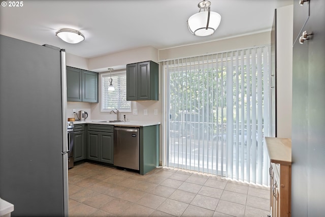 kitchen featuring appliances with stainless steel finishes, gray cabinets, a sink, and light countertops