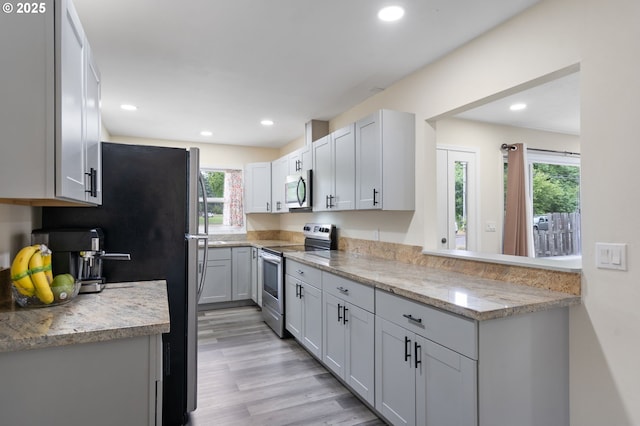 4220 SE 130th Ave, Portland, OR 97236 - kitchen featuring appliances with stainless steel finishes, recessed lighting, light wood-type flooring, and light stone countertops