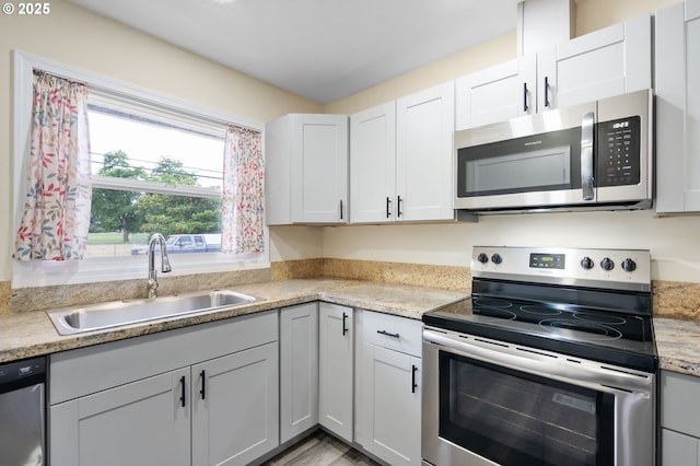 4220 SE 130th Ave, Portland, OR 97236 - kitchen with stainless steel appliances, light countertops, white cabinetry, and light wood-style flooring