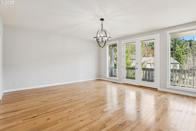 unfurnished dining area with an inviting chandelier, baseboards, and light wood-style flooring