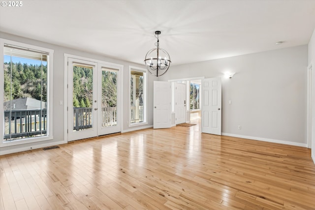 unfurnished dining area featuring baseboards, visible vents, light wood-type flooring, and a chandelier