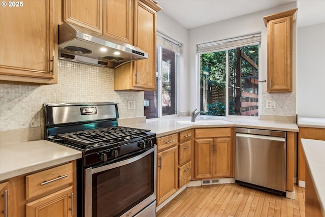 kitchen with visible vents, under cabinet range hood, a sink, light wood finished floors, and stainless steel appliances