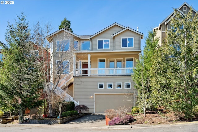 view of front facade featuring stairs, an attached garage, concrete driveway, and covered porch