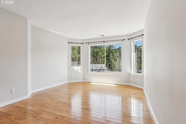 empty room featuring light wood-type flooring, baseboards, and visible vents