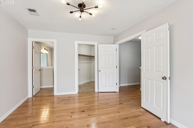 unfurnished bedroom with visible vents, light wood-style floors, and baseboards