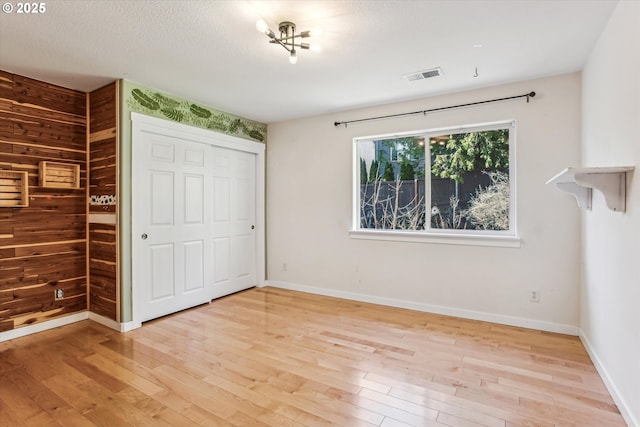 unfurnished bedroom featuring visible vents, baseboards, wood finished floors, and a closet