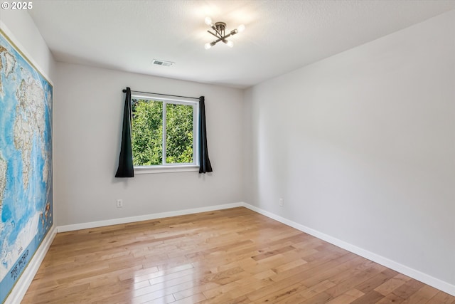 empty room featuring light wood-style floors, baseboards, and visible vents