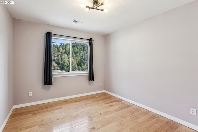 empty room with baseboards, wood finished floors, and visible vents