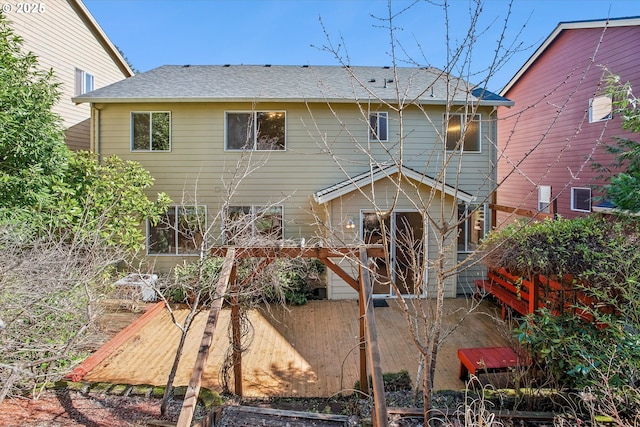 rear view of house featuring fence and roof with shingles