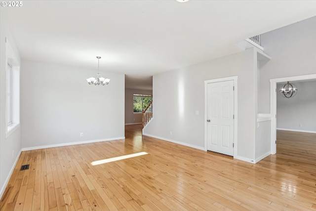 empty room with baseboards, an inviting chandelier, and light wood-style floors