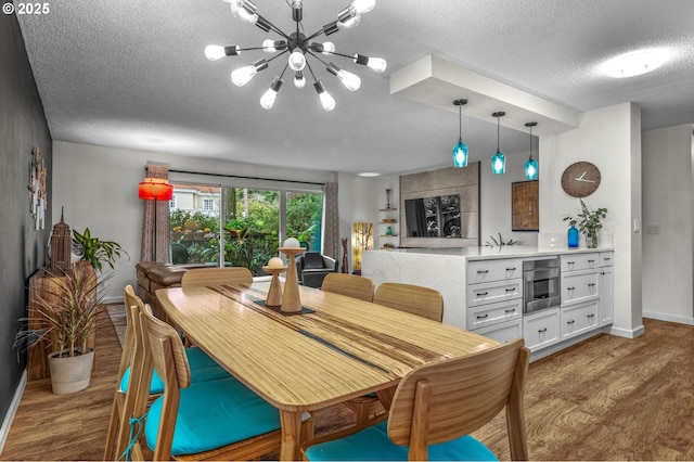 2393 SW Park Pl Unit 113, Portland, OR 97205 - dining area with wood finished floors, baseboards, a textured ceiling, and a chandelier