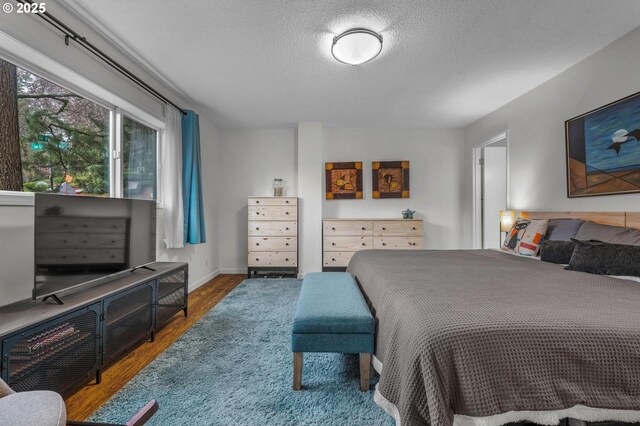 2393 SW Park Pl Unit 113, Portland, OR 97205 - bedroom with wood finished floors, a textured ceiling, and baseboards