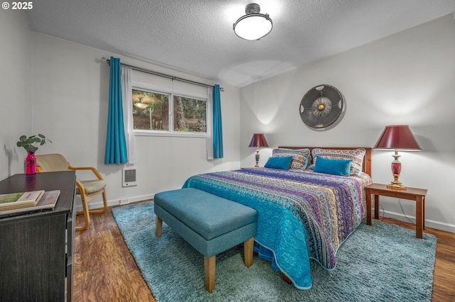 2393 SW Park Pl Unit 113, Portland, OR 97205 - bedroom with a textured ceiling, baseboards, wood finished floors, and heating unit