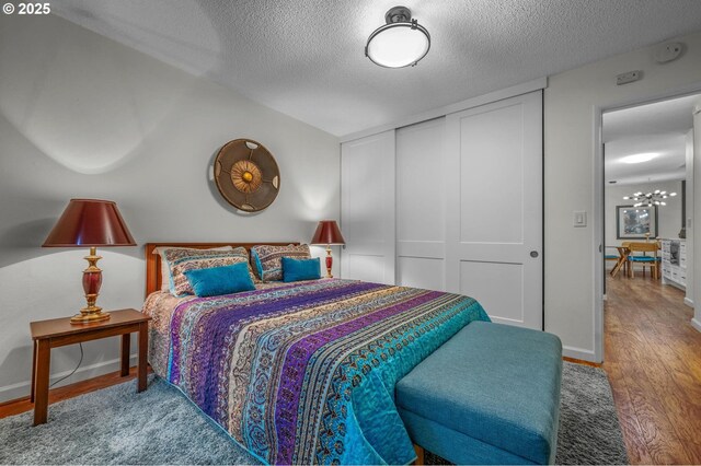 2393 SW Park Pl Unit 113, Portland, OR 97205 - bedroom featuring a textured ceiling, wood finished floors, a closet, and baseboards