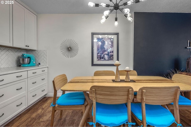 2393 SW Park Pl Unit 113, Portland, OR 97205 - dining area featuring a chandelier, dark wood-style flooring, and a textured ceiling