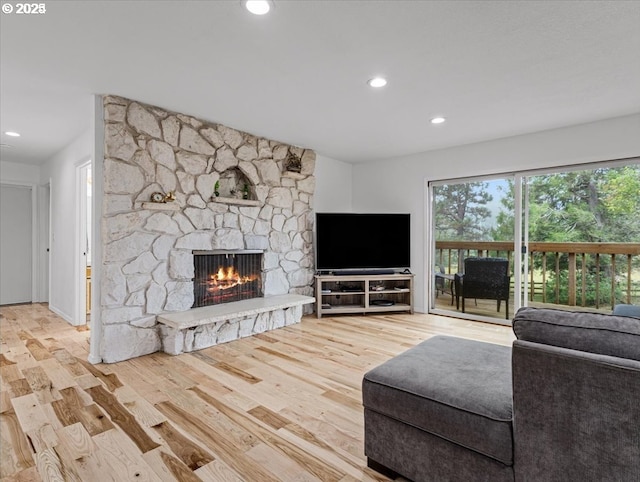 living area featuring recessed lighting, a stone fireplace, and wood finished floors
