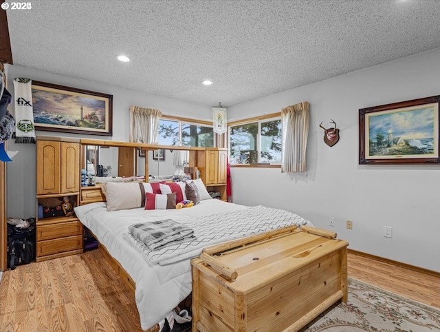 bedroom with recessed lighting, light wood-type flooring, a textured ceiling, and baseboards