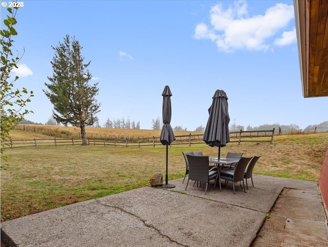 view of patio featuring a rural view, fence, and outdoor dining space