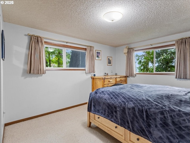carpeted bedroom featuring baseboards and a textured ceiling