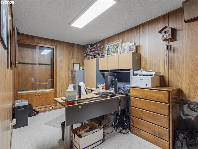 carpeted home office with wood walls and a textured ceiling