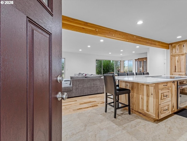 kitchen featuring black electric cooktop, light countertops, a breakfast bar, wall oven, and recessed lighting