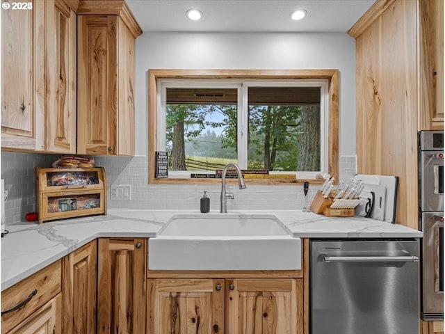 kitchen with tasteful backsplash, a sink, recessed lighting, light stone countertops, and stainless steel dishwasher