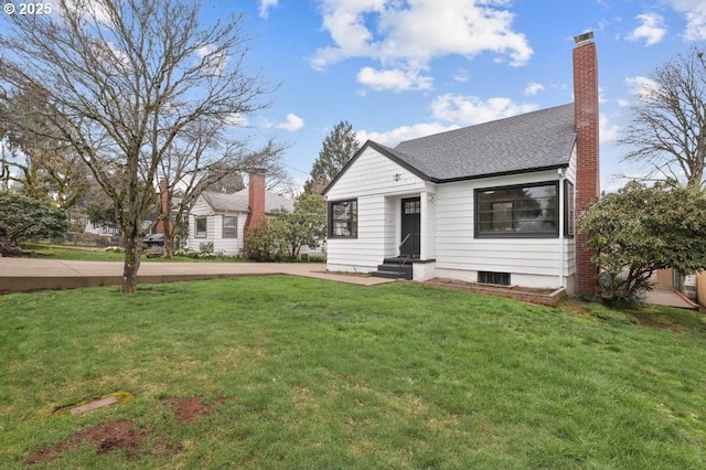 bungalow featuring entry steps, a chimney, a front yard, and roof with shingles