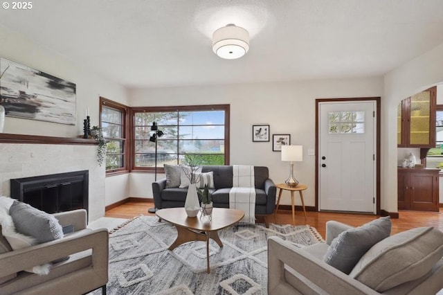 living room with a fireplace with flush hearth, baseboards, and wood finished floors