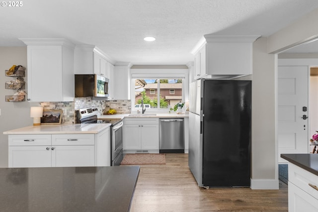 6696 Doral Dr SE, Salem, OR 97306 - kitchen with stainless steel appliances, tasteful backsplash, wood finished floors, white cabinets, and a textured ceiling