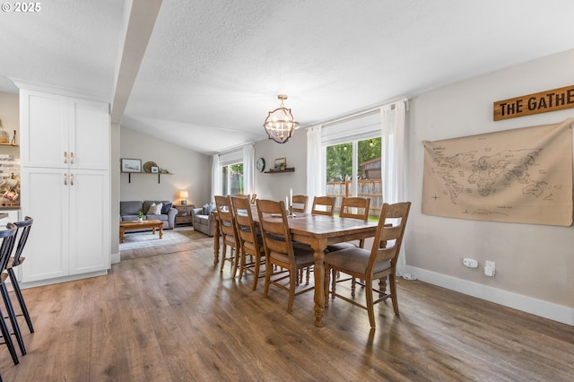 6696 Doral Dr SE, Salem, OR 97306 - dining space featuring wood finished floors, a chandelier, vaulted ceiling, baseboards, and a textured ceiling