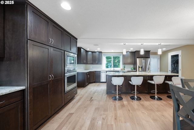 1412 SW Chastain Ave, Gresham, OR 97080 - kitchen featuring stainless steel appliances, a breakfast bar area, light wood finished floors, dark brown cabinets, and recessed lighting