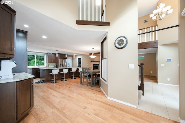 1412 SW Chastain Ave, Gresham, OR 97080 - kitchen featuring a kitchen bar, dark brown cabinets, stainless steel fridge, light wood-style flooring, and a high ceiling