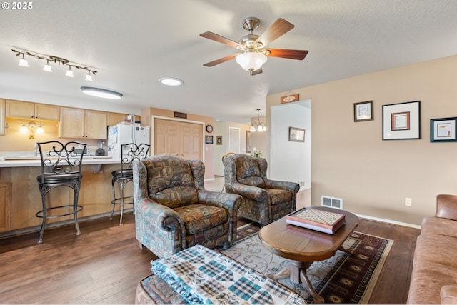 living room with ceiling fan, dark hardwood / wood-style floors, and a textured ceiling