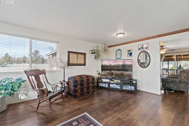 sitting room with dark wood-type flooring, ceiling fan, ornamental molding, and a textured ceiling