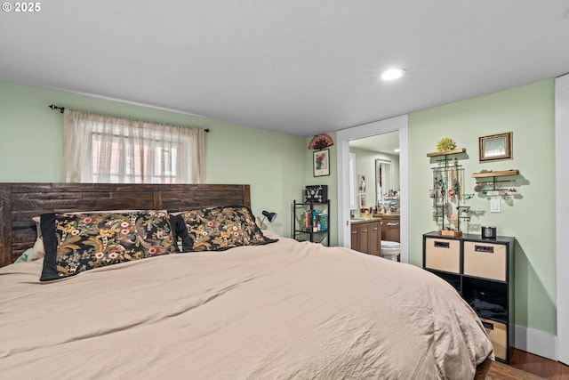 bedroom with hardwood / wood-style floors and ensuite bath