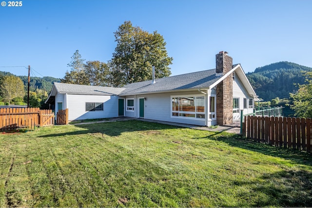 rear view of property with a yard and a mountain view