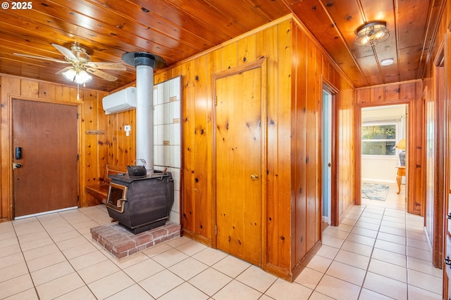 entrance foyer with light tile patterned floors, a wood stove, wooden ceiling, an AC wall unit, and wood walls